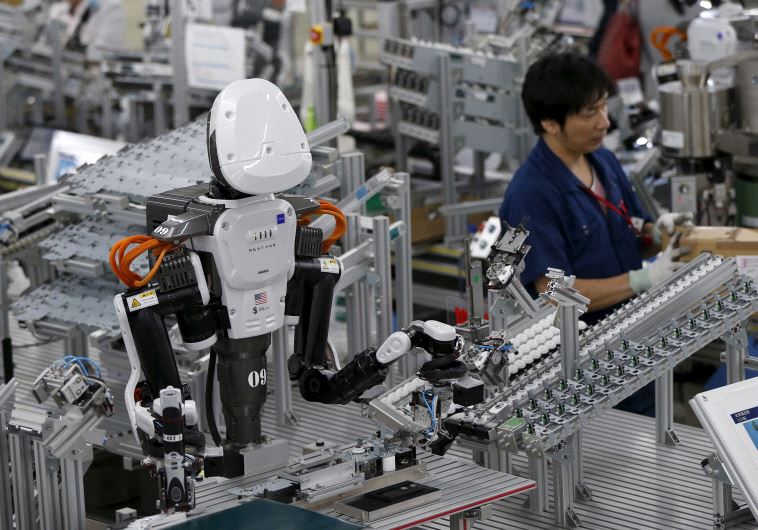 A humanoid robot works side by side with employees in the assembly line at a factor