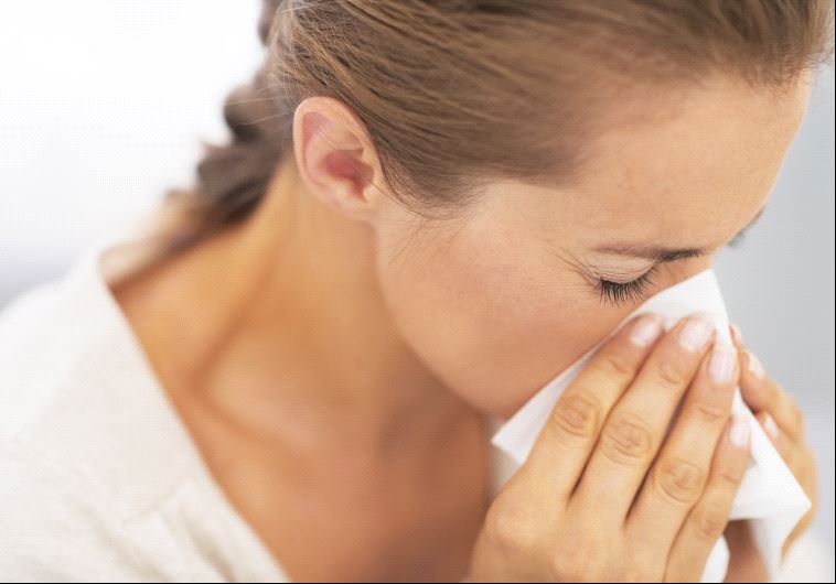 A woman blowing her nose into a tissue, possibly after or sneeze or while sick