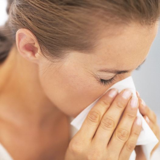 A woman blowing her nose into a tissue, possibly after sneeze or while sick