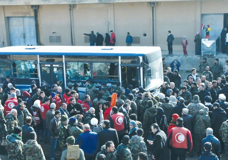 PEOPLE WAIT for buses after being displaced by fighting near Aleppo in Syria