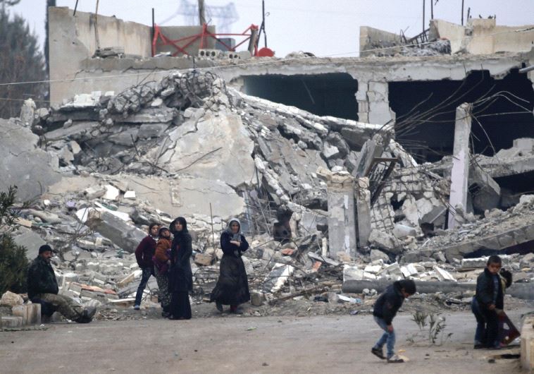 People stand near near rubble of damaged buildings in the northern Aleppo countryside in Syria in December 2016