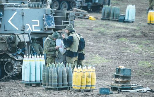 IDF SOLDIERS stand next to ammunition and a mobile artillery unit near the border with Syria last year.