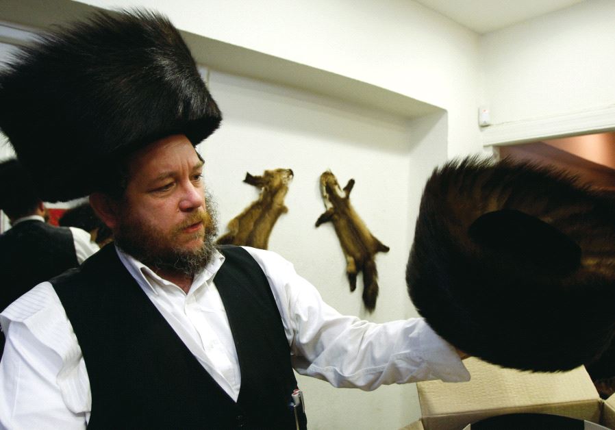 Illustrative photo of a man wearing and holding a shtreimel, a fur hat
