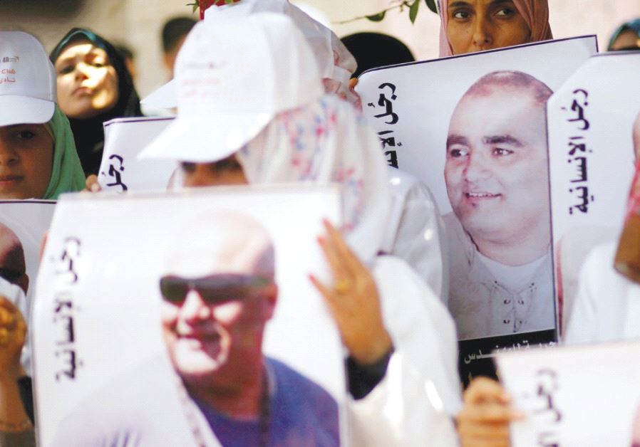 PALESTINIANS HOLD POSTERS of Mohammad El Halabi, World Vision’s manager of operations in the Gaza Strip, at a protest to show support for him in Gaza City on August 7.