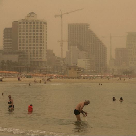 BEACHGOERS in Tel Aviv ignore the August 2015 sand and dust storm to take a swim. (