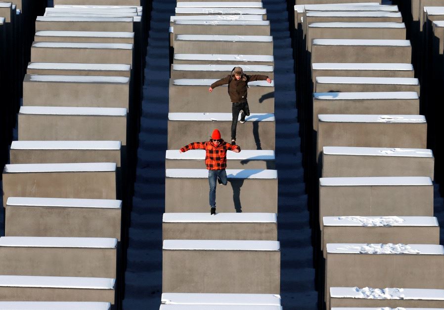 People jump from concrete elements of the Holocaust memorial in Berlin