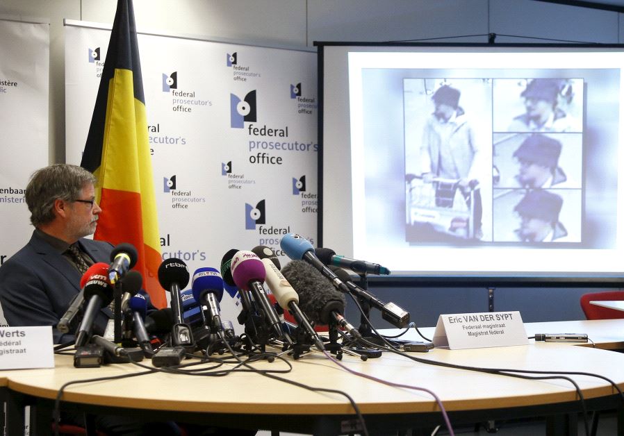 Belgian federal prosecutor Eric Van Der Sypt looks at CCTV images of a suspect in the attack which took place at the Brussels international airport of Zaventem, projected on a screen during a news conference in Brussels, Belgium April 7, 2016