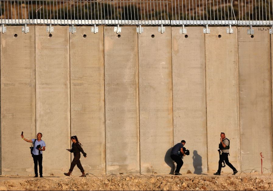 Security personnel walk in front of the barrier with the West Bank near Havat Ella, 20 km. southwest of Hebron.