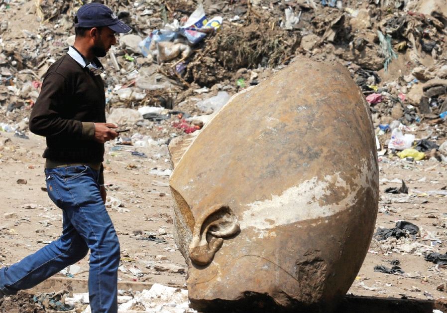 A MAN PASSES by part of the head of an unearthed statue said to be of 13th-century BCE Pharaoh Ramses the Great, in Cairo on Thursday.