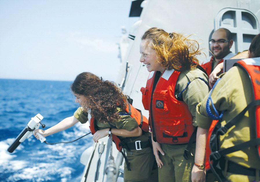 A NAVAL OFFICER takes a measurement during a drill at sea.