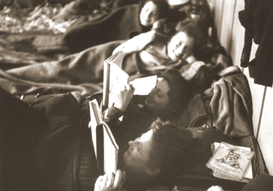Jewish women rescued from Theresienstadt read while resting on their beds in the Hadwigschulhaus in St. Gallen, Switzerland