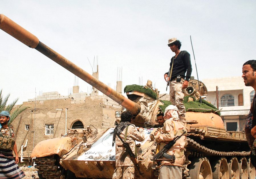 PRO-GOVERNMENT FIGHTERS gather next to a tank they use in the fighting against Houthi fighters in the southwestern city of Taiz in Yemen.