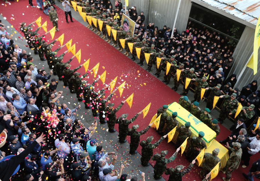 PEOPLE TOSS rose petals as Hezbollah members stand near the coffin of top Hezbollah commander Mustafa Badreddine, who was killed in an attack in Syria last year