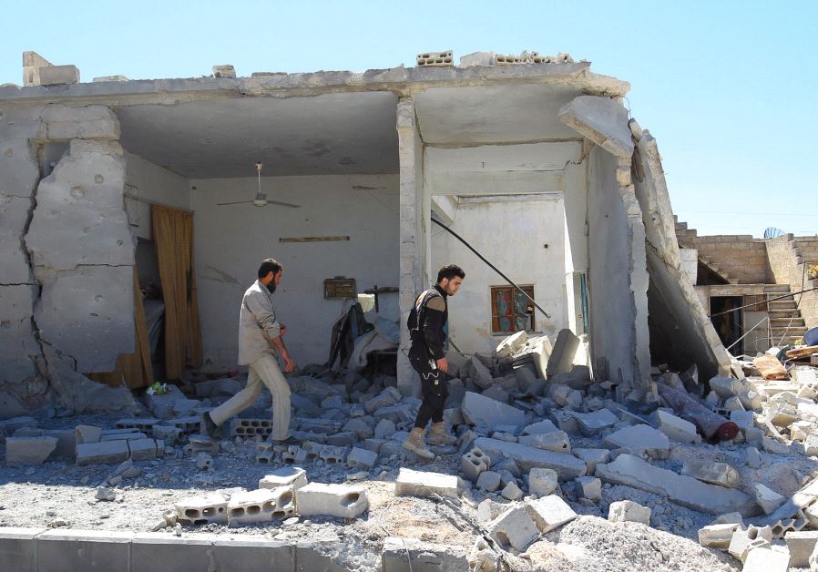 SYRIAN CIVIL DEFENSE members inspect the damage at a site hit by air strikes on Tuesday, in the town of Khan Sheikhoun in rebel-held Idlib