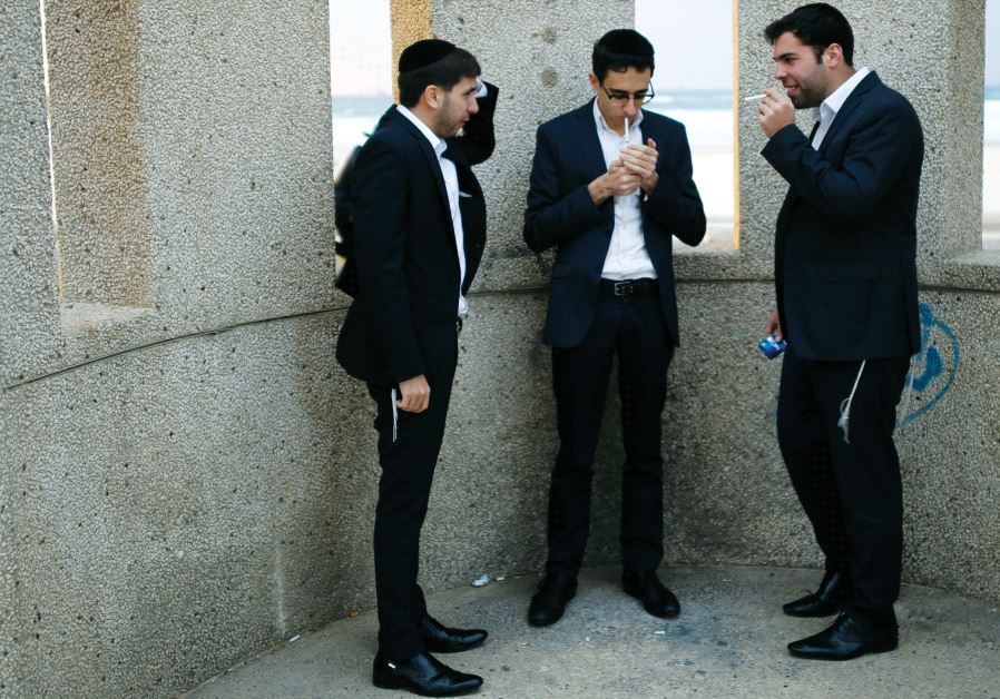 Utra-orthodox men smoke cigarettes near the beach in Ashdod