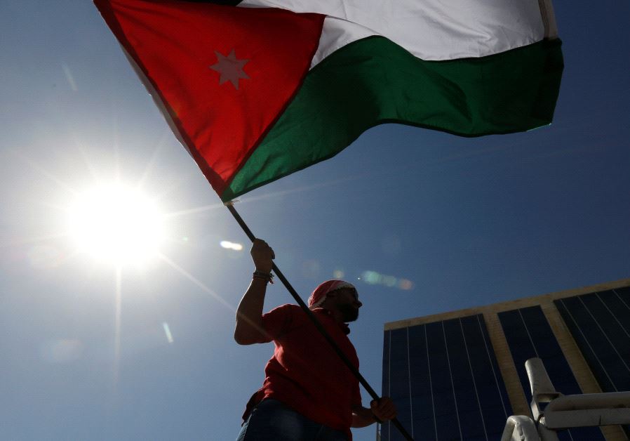 A Jordanian protester holds a Jordanian national flag