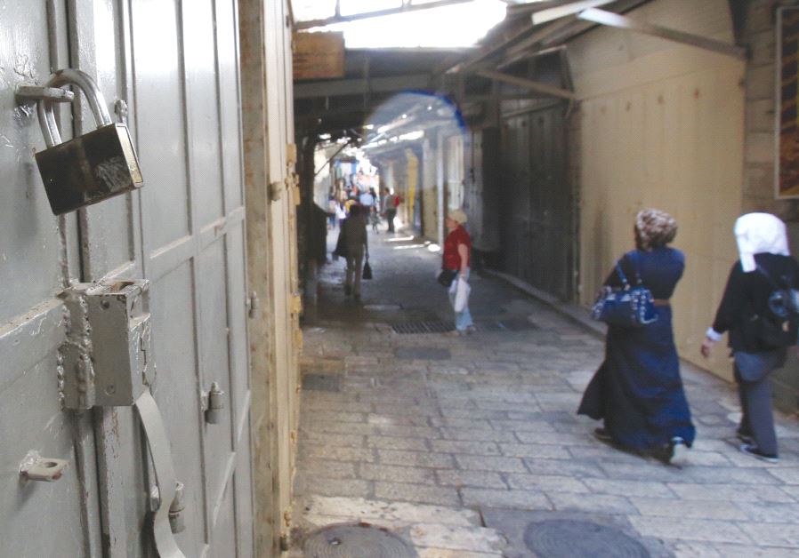 PEOPLE WALK past one of the more than 1,400 closed shops in the Muslim Quarter in the Old City of Jerusalem on April 27, 2017