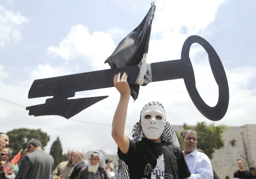 A Palestinian wearing a mask holds a cut-out of a key during a rally ahead of the ‘Nakba Day’ in Bethlehem in 2015