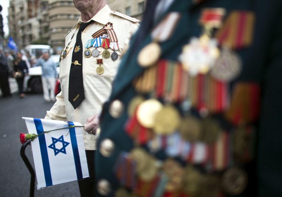 A World War Two veteran holds a flower and Israel's national flag during a march in Jerusalem commemorating the 70th anniversary of VE (Victory in Europe) Day May 10, 2015