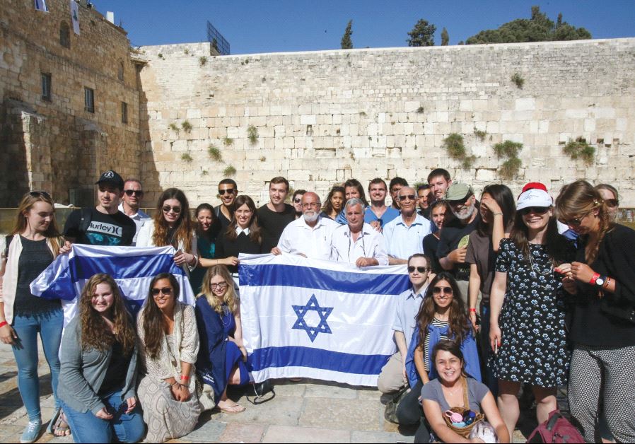 DEPUTY FOREIGN MINISTER Tzipi Hotovely (standing behind left corner of flag) and the three paratroopers from David Rubinger’s iconic 1967 photo (in white shirts) pose with international students at the Western Wall May 11, 2017