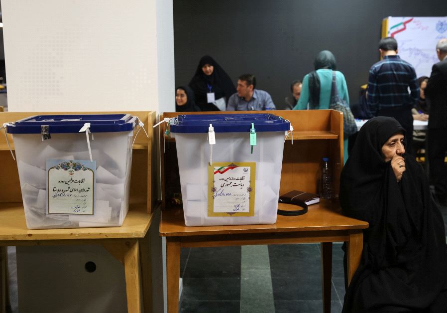 Electoral employees sits next to ballot boxes before closing vote for the presidential election in a polling station in Tehran, Iran, May 19, 2017.