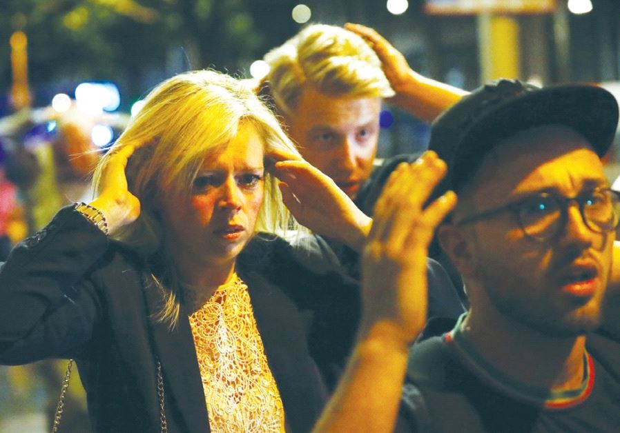 PEOPLE LEAVE the area of Saturday night’s terrorist attack near London Bridge with their arms raised to indicate they are not a danger.
