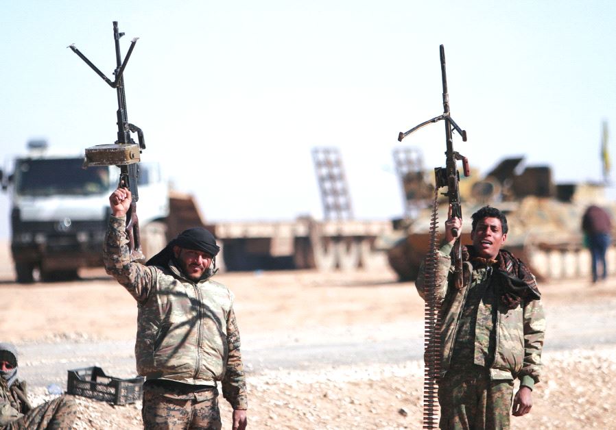 SYRIAN DEMOCRATIC Forces fighters hold up their weapons north of Raqqa city.