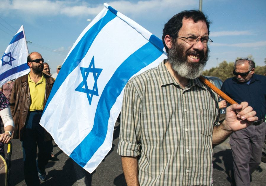 Jewish settlers hold Israeli flags during a protest in Tekoa in November 2013