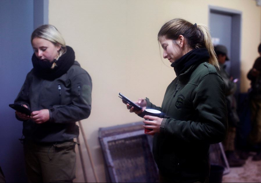 Female Israeli soldiers from the Haraam artillery battalion use their mobile phones as they stand in the women's living quarters at a military base in the Golan Heights March 1, 2017. 