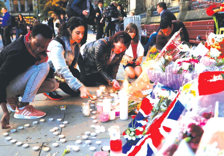 Women light candles for the victims of the Manchester Arena attack last month