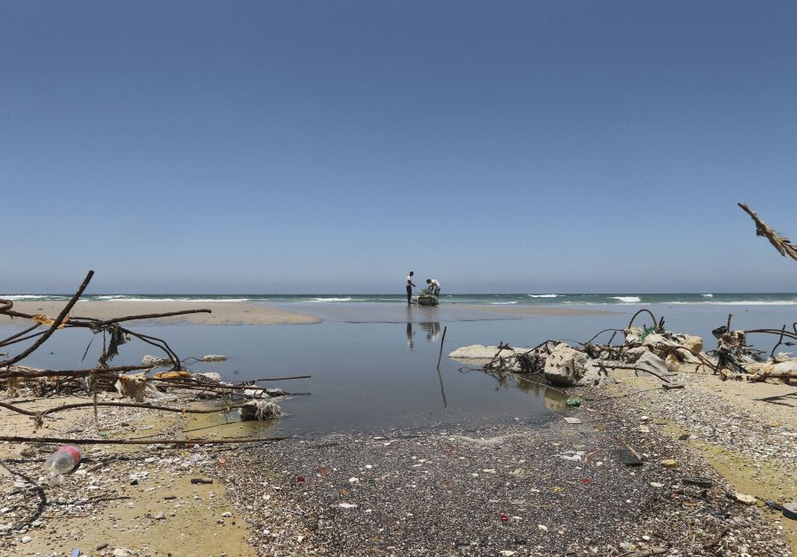 Palestinian fishermen are reflected in wastewater as they prepare their boat on a beach in the central Gaza Strip June 26, 2014.