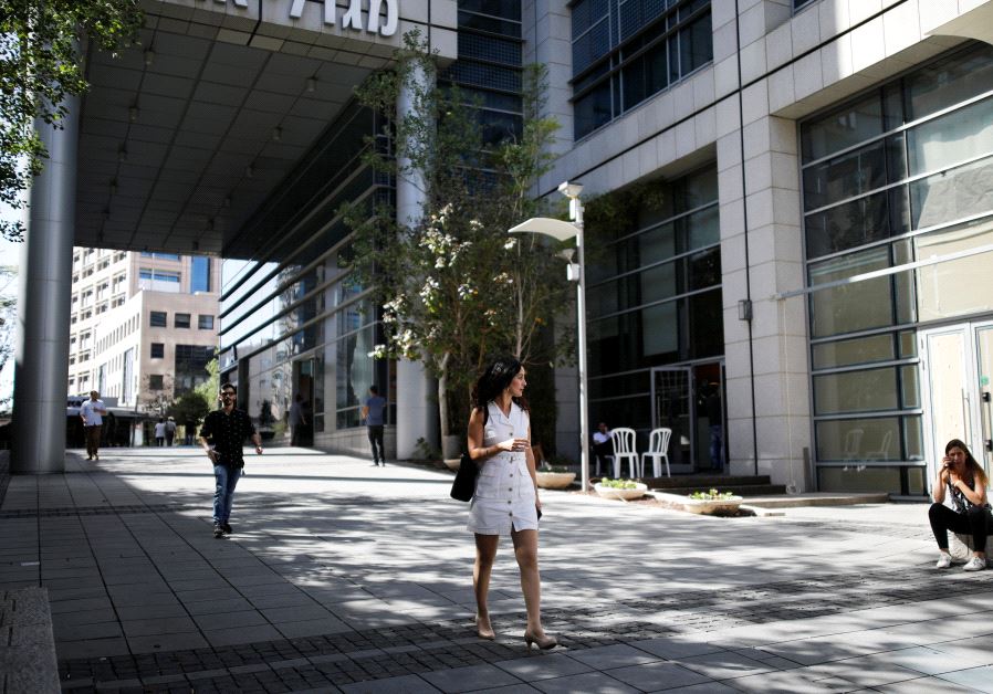 A woman walks near high-rise buildings in the hi-tech business area of Tel Aviv