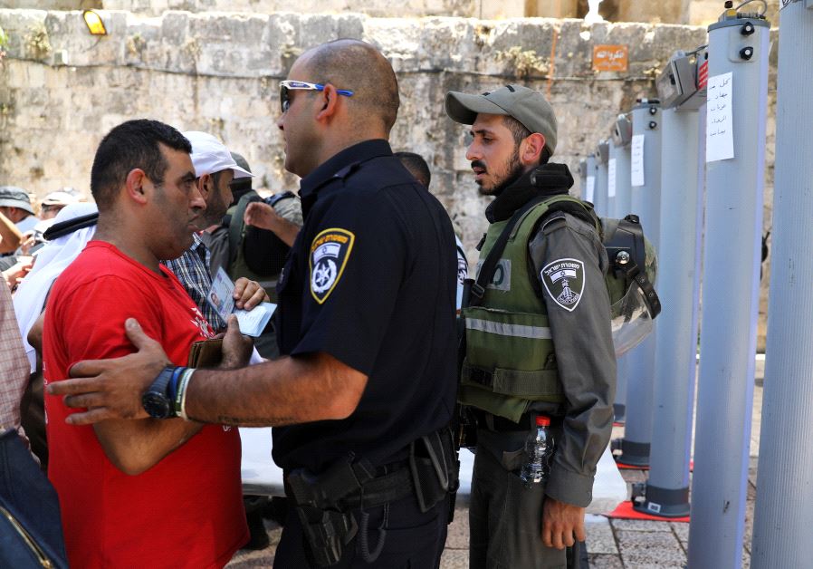An Israeli police officer checks the identity of a Palestinian man next to newly installed metal detectors at an entrance to the compound known to Muslims as Noble Sanctuary and to Jews as Temple Mount, in Jerusalem's Old City July 16, 2017.