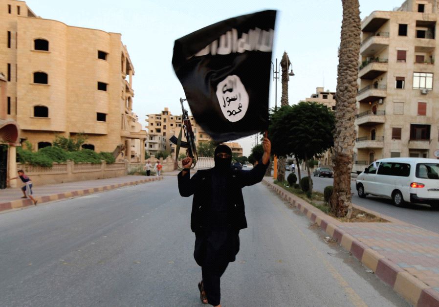 A MEMBER of ISIS waves the group’s flag in Raqqa