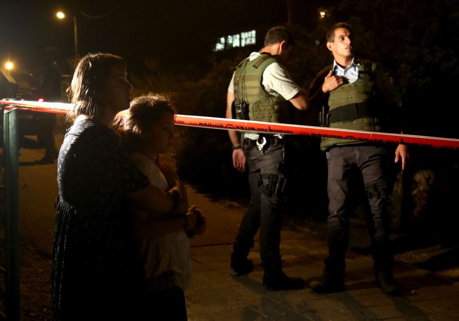Israeli comfort each others outside the home, where a Palestinian broke in the day before and stabbed four Israelis killing three of them, in the Jewish settlement Neve Tsuf (Halamish), in the West Bank, on July 22, 2017
